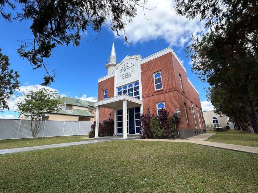 Foto sebuah mushaf Al-Quran tua yang terbuka di atas meja kayu di dalam perpustakaan klasik Islam, dikelilingi oleh tumpukan kitab kuning (turats) dengan cahaya remang-remang yang menciptakan suasana khusyuk dan penuh ilmu.