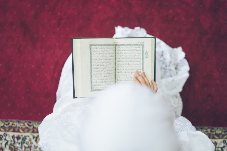 Foto sebuah mushaf Al-Quran yang terbuka di atas meja kayu di dalam perpustakaan klasik dengan cahaya hangat menyinari lembaran teks Arab, menciptakan suasana tenang dan penuh ilmu.