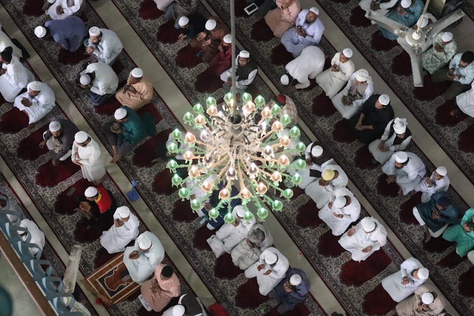 Foto sebuah mushaf Al-Quran tua yang terbuka di atas meja kayu di dalam sebuah perpustakaan klasik dengan pencahayaan hangat yang masuk dari jendela masjid, menciptakan suasana spiritual dan ilmiah yang mendalam.