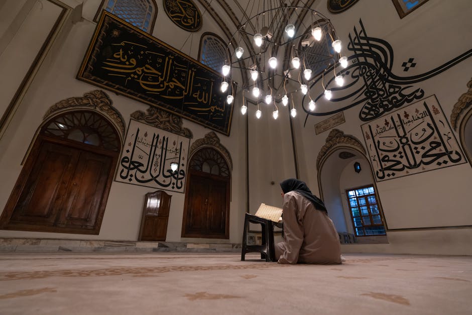 Foto sebuah naskah manuskrip hadits kuno dengan tinta emas yang diletakkan di atas meja kayu jati di dalam perpustakaan masjid yang tenang dengan cahaya matahari pagi yang masuk melalui jendela tinggi.