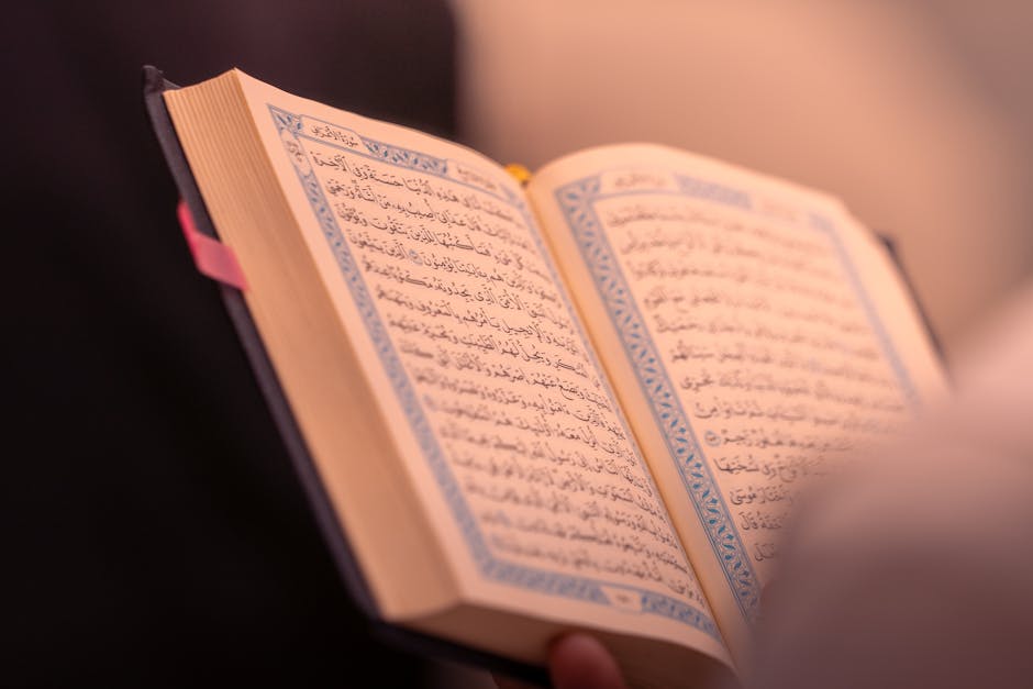 Foto sebuah naskah klasik kitab hadits yang terbuka di atas meja kayu tua dengan pencahayaan hangat dari jendela masjid, menciptakan suasana ilmiah dan religius yang mendalam.
