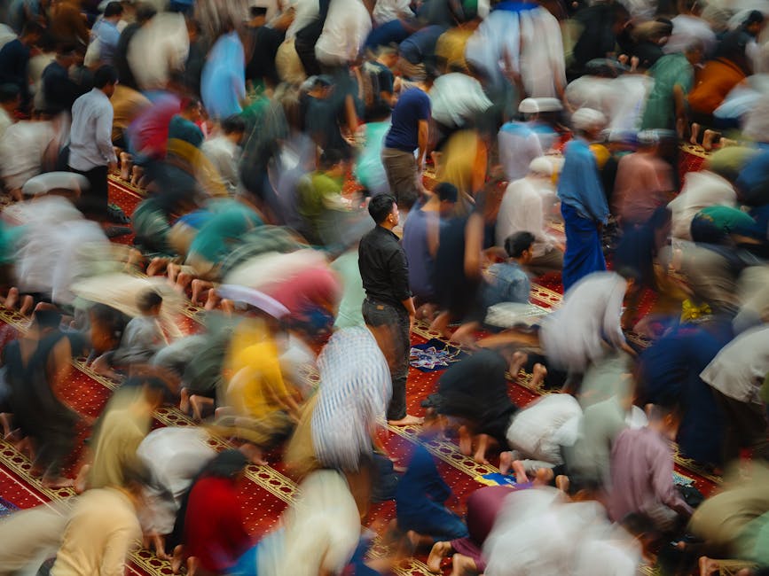 Suasana pengiriman bantuan kemanusiaan berupa peti kemas berlogo lembaga bantuan Islam internasional di sebuah pelabuhan besar, dengan latar belakang bendera negara-negara Muslim yang berkibar berdampingan sebagai simbol persatuan umat.