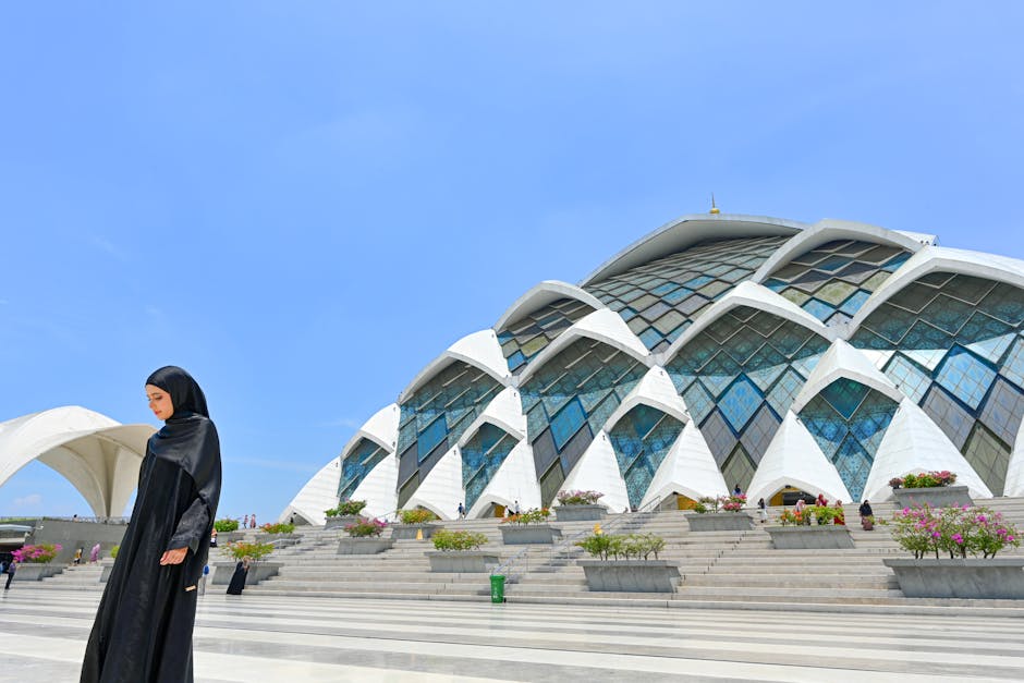 Foto udara yang memperlihatkan truk-truk bantuan kemanusiaan dengan bendera Indonesia dan logo lembaga kemanusiaan Islam sedang bersiap memasuki perbatasan wilayah konflik, dikelilingi oleh para relawan yang sedang berdoa bersama.