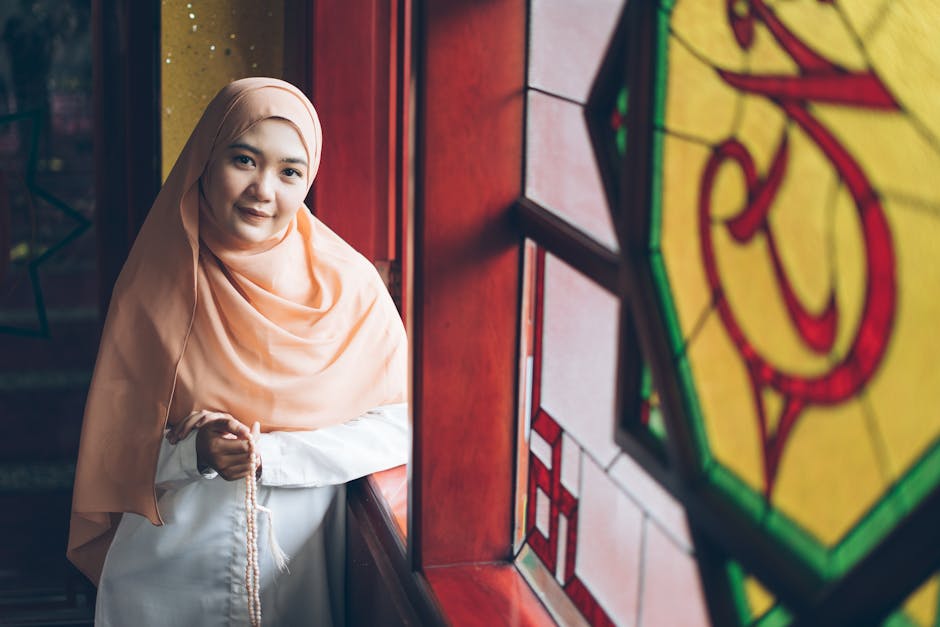 Foto sebuah naskah kuno kitab kuning klasik yang terbuka di atas meja kayu dengan latar belakang rak buku perpustakaan Islam yang megah dan cahaya matahari yang masuk melalui jendela masjid.