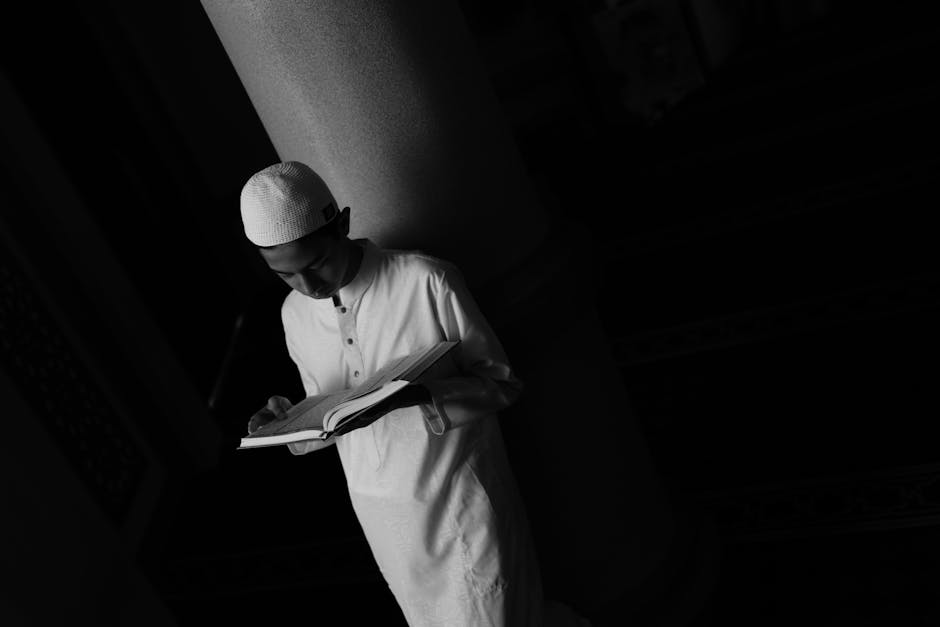 Foto sebuah meja kayu tua di dalam perpustakaan klasik dengan tumpukan kitab-kitab kuning tebal, sebuah mushaf Al-Quran yang terbuka dengan khat yang indah, dan sebuah pena bulu tradisional, menciptakan suasana keilmuan yang mendalam dan tenang.