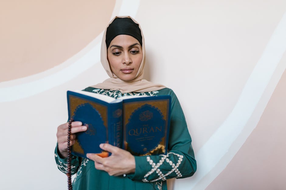 Foto sebuah naskah klasik kitab fiqih kuno dengan tulisan tangan Arab yang indah, diletakkan di atas meja kayu tua di dalam sebuah perpustakaan Islam yang memiliki pencahayaan hangat dan rak-rak buku yang penuh dengan kitab-kitab tebal di latar belakang.