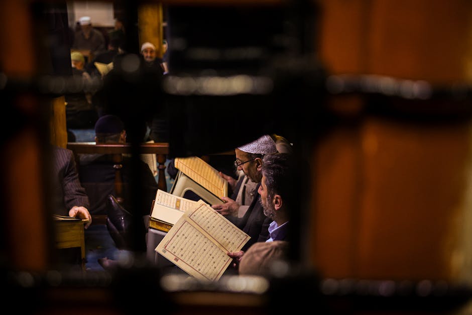 Foto sebuah naskah kuno kitab kuning berharakat lengkap yang diletakkan di atas meja kayu di dalam perpustakaan masjid tradisional, dengan cahaya matahari lembut yang masuk melalui jendela kisi-kisi, menciptakan suasana tenang dan penuh nuansa keilmuan.