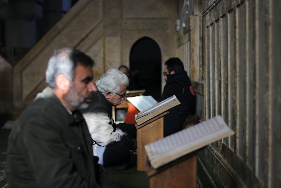 Foto naskah kuno kitab tauhid dengan tulisan kaligrafi Arab yang indah di atas meja kayu jati di dalam perpustakaan klasik yang diterangi cahaya lampu temaram yang tenang.