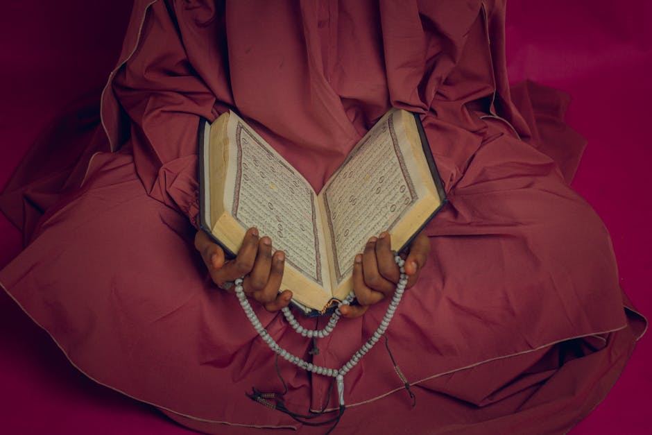 Foto sebuah naskah klasik kitab kuning beraliran teologi Asy’ariyah yang terletak di atas meja kayu dengan pencahayaan hangat dari lampu perpustakaan tua yang tenang.