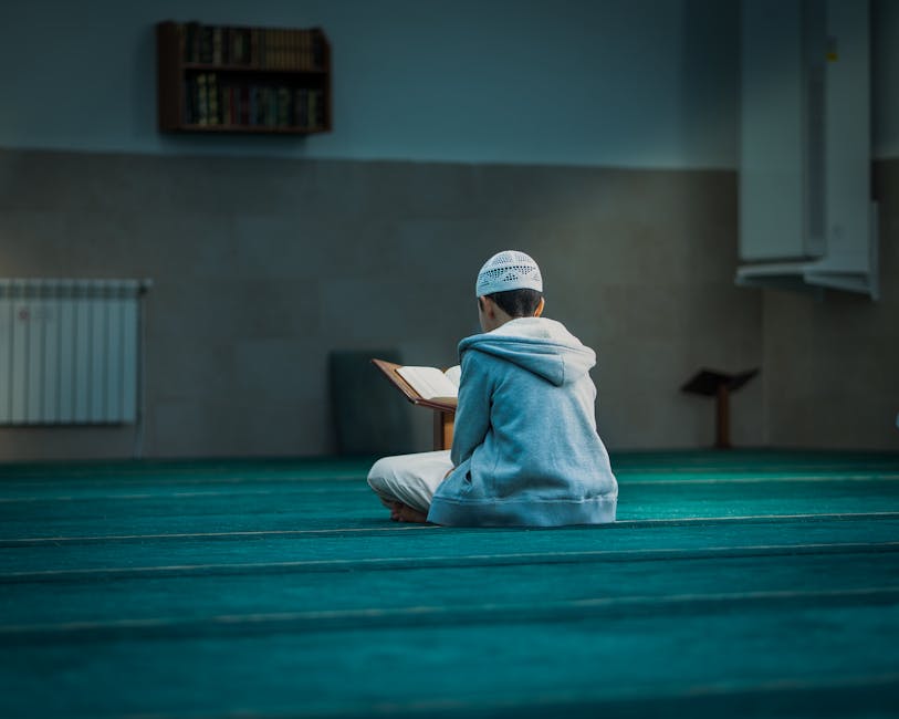 Foto sebuah naskah kuno kitab kuning klasik tentang ilmu tauhid yang terbuka di atas meja kayu jati dengan pencahayaan hangat di dalam perpustakaan pesantren yang tenang, menampilkan kaligrafi Arab yang indah dan catatan pinggir khas ulama terdahulu.