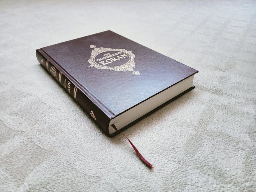 Foto sebuah mushaf Al-Quran yang terbuka di atas meja kayu di dalam sebuah perpustakaan klasik dengan cahaya temaram yang tenang, menciptakan suasana ilmiah dan spiritual yang mendalam.