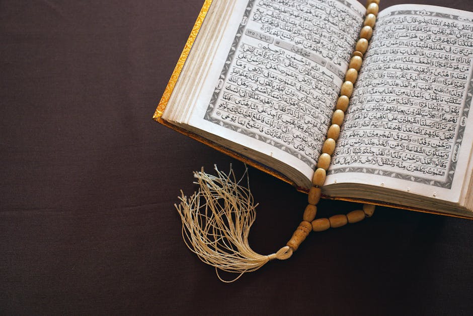 Foto sebuah mushaf Al-Quran yang terbuka di atas meja kayu di dalam perpustakaan klasik dengan cahaya hangat, melambangkan kedalaman ilmu dan ketenangan spiritual dalam mengkaji teks agama.