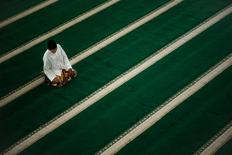 Foto sebuah mushaf Al-Quran tua yang terbuka di atas meja kayu di dalam sebuah perpustakaan klasik dengan pencahayaan temaram yang memberikan kesan tenang dan sakral, dikelilingi oleh tumpukan kitab-kitab turats para ulama.