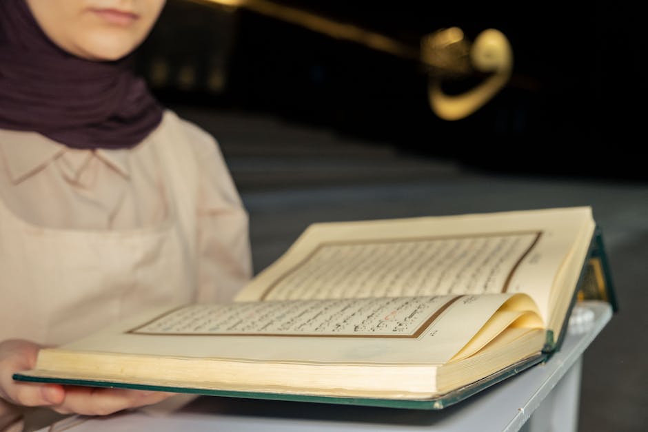Foto sebuah mushaf Al-Quran yang terbuka di atas meja kayu di dalam perpustakaan masjid yang tenang, dengan cahaya matahari pagi yang masuk melalui jendela, menciptakan suasana yang penuh kedamaian dan keilmuan.