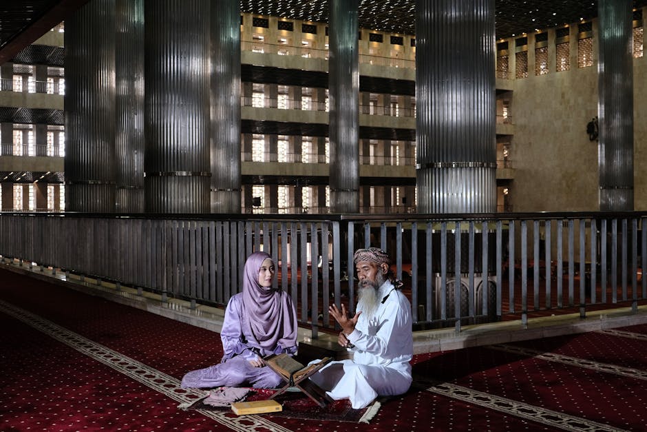 Foto naskah kuno Al-Quran dengan tulisan kaligrafi yang indah di atas meja kayu jati, dikelilingi oleh tumpukan kitab-kitab turats di dalam sebuah perpustakaan Islam yang tenang dan bercahaya hangat.