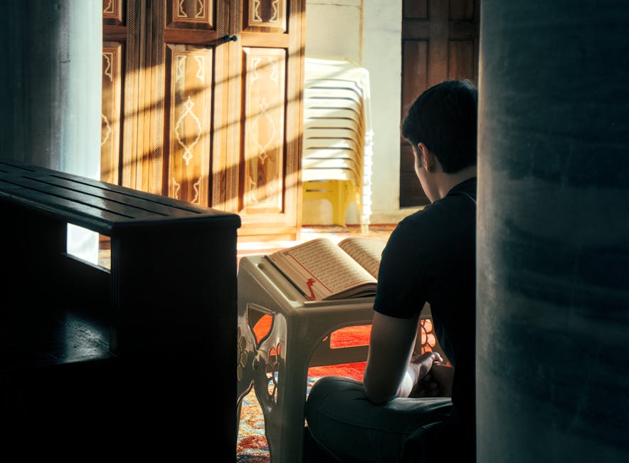 Foto sebuah naskah klasik kitab tauhid dengan tulisan kaligrafi Arab yang indah di atas meja kayu tua, disinari cahaya matahari pagi yang masuk melalui jendela masjid, menciptakan suasana ilmiah dan spiritual yang mendalam.