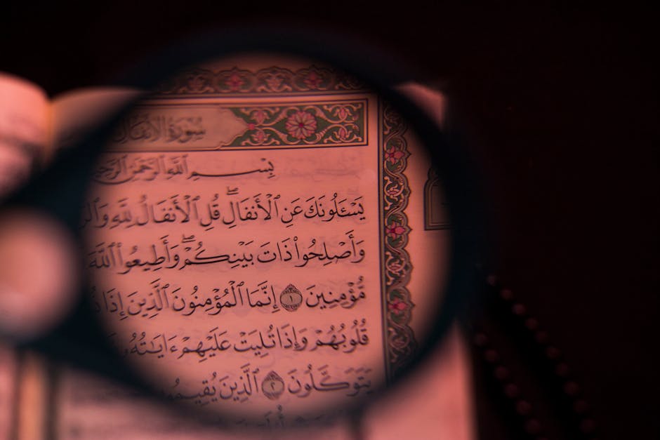 Foto sebuah mushaf Al-Quran tua yang terbuka dengan tulisan kaligrafi yang indah, diletakkan di atas meja kayu di dalam perpustakaan klasik dengan latar belakang deretan kitab-kitab kuning yang tersusun rapi di rak kayu.