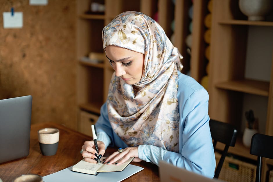 Ilustrasi seorang perempuan Muslimah yang sedang membaca buku dengan latar belakang rak buku yang rapi dan jendela yang memancarkan cahaya pagi, melambangkan pencarian ilmu dan harapan masa depan peradaban.