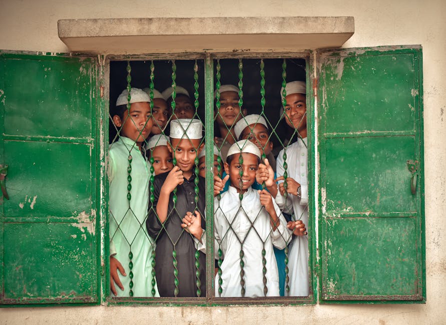 Seorang pemuda Muslim milenial duduk santai di sebuah coffee shop modern yang penuh tanaman hijau, ia sedang menatap laptop dengan ekspresi tenang sambil memegang cangkir kopi, mencerminkan suasana produktif yang tetap damai.