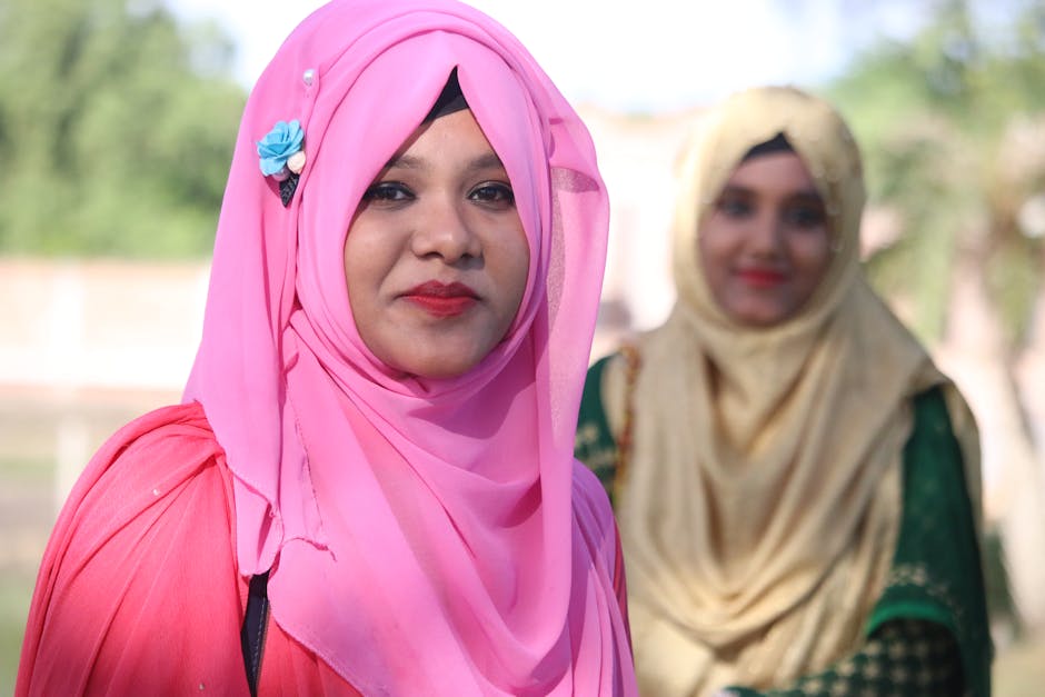 Seorang pemuda Muslim mengenakan hoodie modern sedang duduk santai di sebuah kafe estetik yang minimalis, sambil memegang buku catatan dan tersenyum tenang menatap layar laptopnya yang menampilkan desain kreatif.