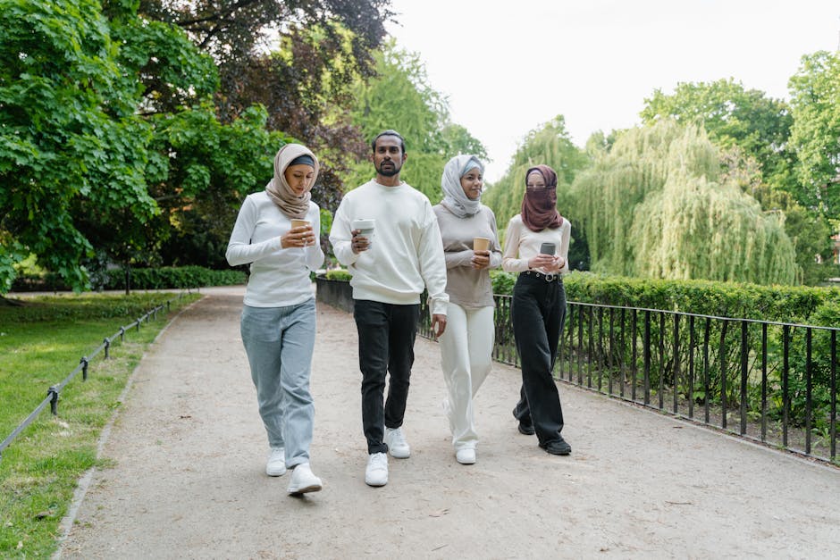 Seorang pemuda Muslim mengenakan hoodie modern dan headphone sedang duduk santai di sebuah kafe minimalis, ia tersenyum sambil melihat pemandangan di luar jendela dengan suasana cahaya matahari sore yang hangat dan estetik.