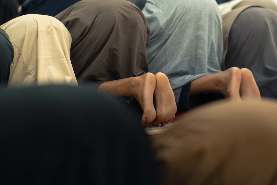 Deskripsi gambar: Seorang pemuda Muslim mengenakan hoodie modern sedang duduk santai di taman kota yang asri sambil mendengarkan earphone dan memegang buku saku doa, menunjukkan suasana tenang di tengah hiruk-pikuk kota.