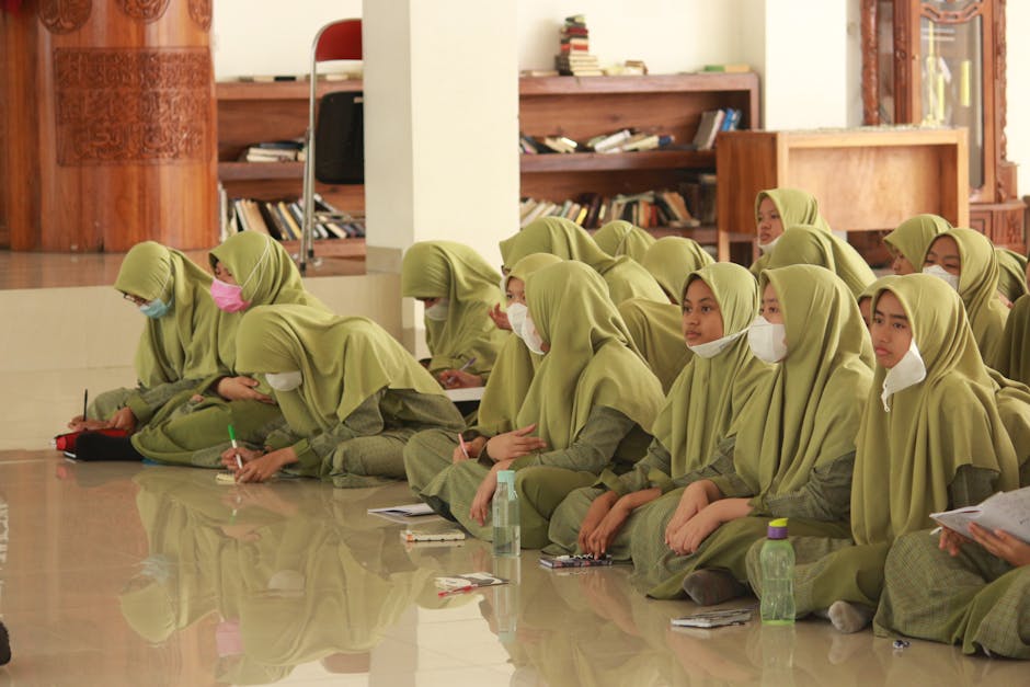 Foto estetik seorang anak muda Muslim sedang duduk tenang di sudut kafe yang minimalis, mengenakan pakaian modern namun sopan, sambil memegang buku catatan dan segelas kopi, dengan cahaya matahari sore yang hangat masuk melalui jendela.