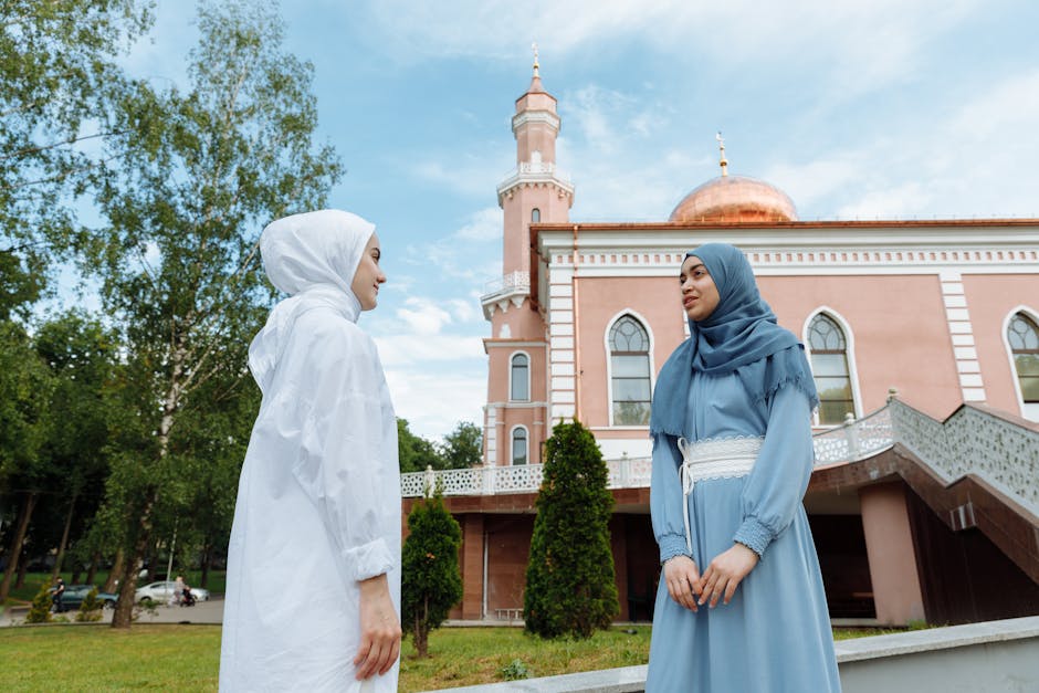Seorang pemuda Muslim mengenakan hoodie modern sedang duduk santai di taman kota yang asri sambil mendengarkan podcast melalui headphone, terlihat tenang dan damai dengan pemandangan kota di latar belakang.