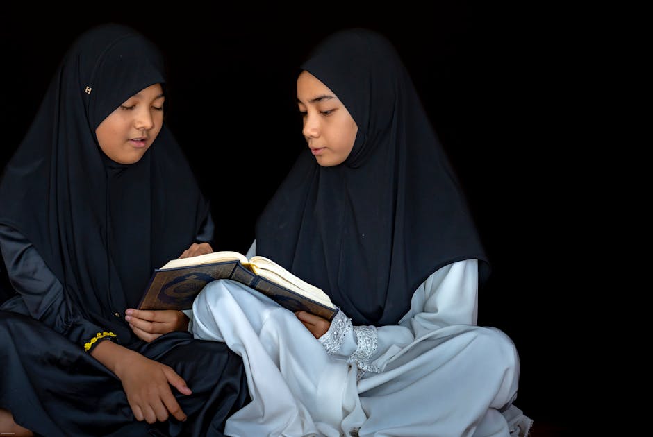Seorang pemuda Muslim duduk santai di sebuah kedai kopi modern yang estetik, sedang melihat ke arah jendela dengan ekspresi tenang, di depannya ada sebuah laptop dan buku catatan kecil, suasana hangat dengan cahaya sore hari.