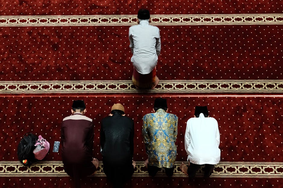 Seorang pemuda Muslim mengenakan hoodie modern sedang duduk santai di sebuah kafe minimalis dengan laptop di depannya, ia tersenyum tipis sambil menatap jendela dengan suasana sore yang hangat.