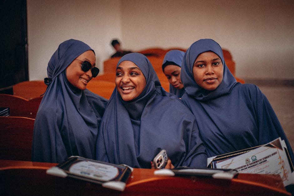 Seorang anak muda Muslim sedang duduk santai di coffee shop yang estetik, memegang segelas kopi sambil menatap pemandangan luar jendela dengan ekspresi tenang, ada laptop dan buku jurnal di depannya dalam suasana cahaya sore yang hangat.