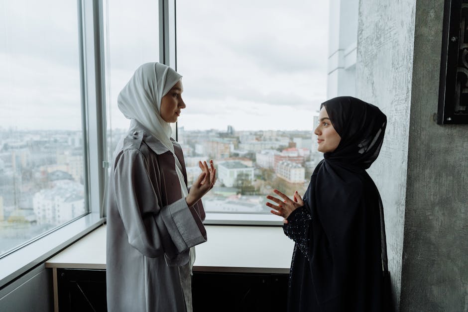 Seorang pemuda Muslim mengenakan hoodie modern sedang duduk santai di taman kota yang asri sambil menutup mata sejenak, terlihat tenang dan damai dengan latar belakang gedung perkotaan yang estetik namun blur.
