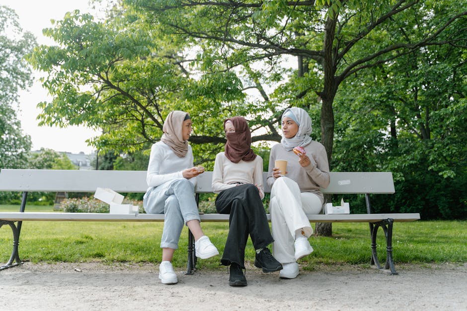 Seorang pemuda Muslim dengan pakaian kasual modern sedang duduk santai di sebuah kafe estetik, memegang secangkir kopi hangat sambil tersenyum menatap ke arah luar jendela, menciptakan suasana yang tenang dan damai.