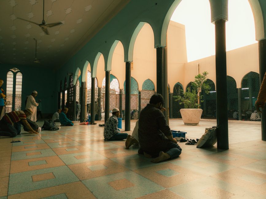 Foto estetik beberapa anak muda Muslim modern, laki-laki dan perempuan berhijab kasual, sedang duduk santai di area outdoor sebuah kafe minimalis sambil berbincang hangat, memegang cangkir kopi, dengan suasana sore hari yang hangat dan menenangkan.