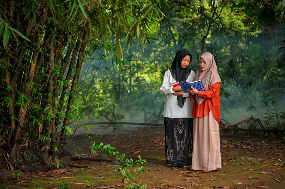 Ilustrasi seorang pemuda Muslim modern sedang duduk santai di sudut kafe estetik, memegang secangkir kopi hangat sambil tersenyum menatap ke luar jendela, dengan mushaf Al-Quran kecil atau buku catatan terbuka di atas meja kayu di depannya.