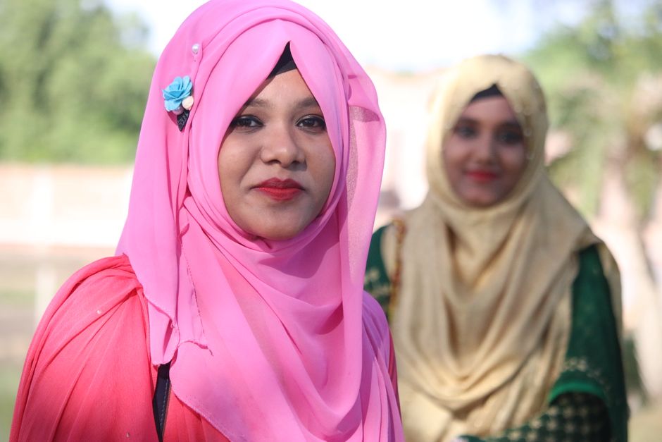 Seorang anak muda Muslim berpakaian kasual modern sedang duduk santai di sudut kafe estetis, membaca buku sambil memegang cangkir kopi dengan pencahayaan sore yang hangat dan tenang.