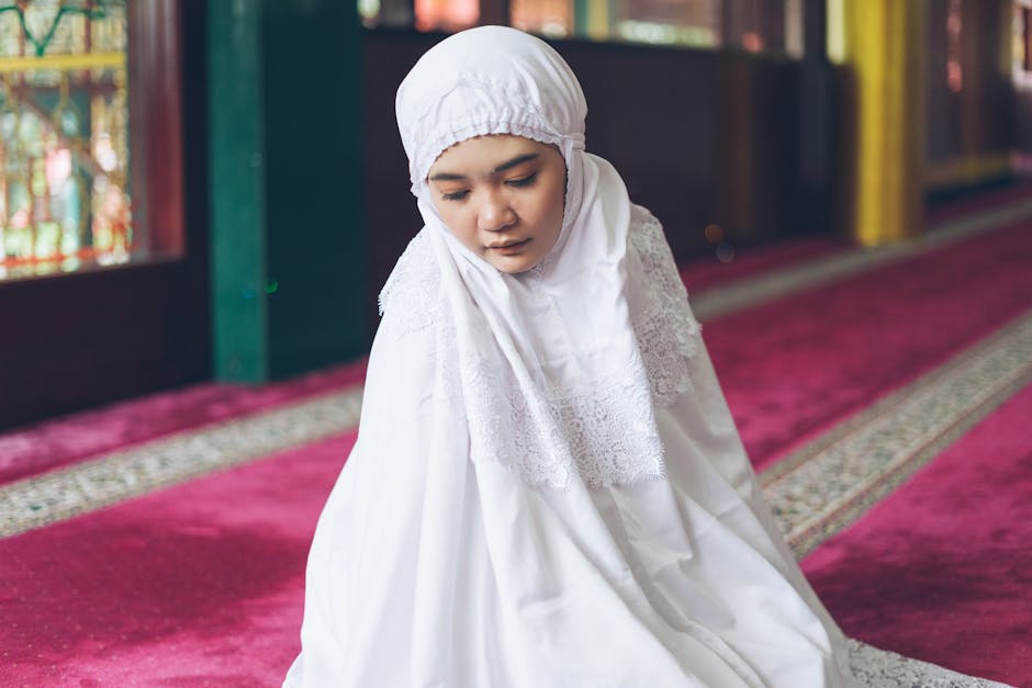 Foto naskah kuno kitab fiqih klasik dengan tulisan tangan khat Arab yang indah, diletakkan di atas meja kayu tua di dalam perpustakaan Islam yang dipenuhi rak buku-buku tebal, menciptakan suasana keilmuan yang mendalam dan berwibawa.