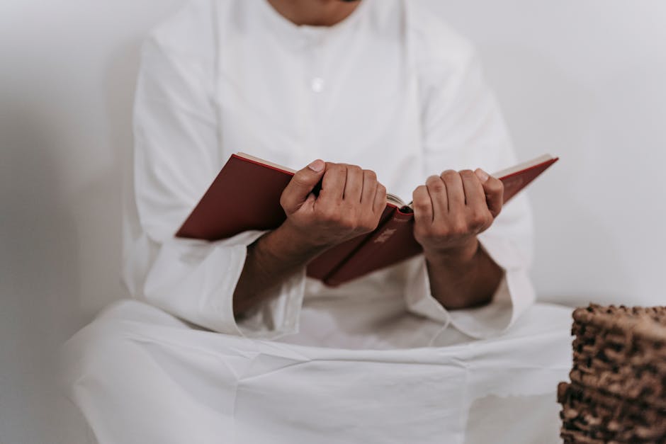 Foto naskah kitab kuning klasik yang terbuka di atas meja kayu dengan pencahayaan hangat, dikelilingi oleh tumpukan buku-buku referensi fiqih di sebuah perpustakaan Islam tradisional yang tenang.