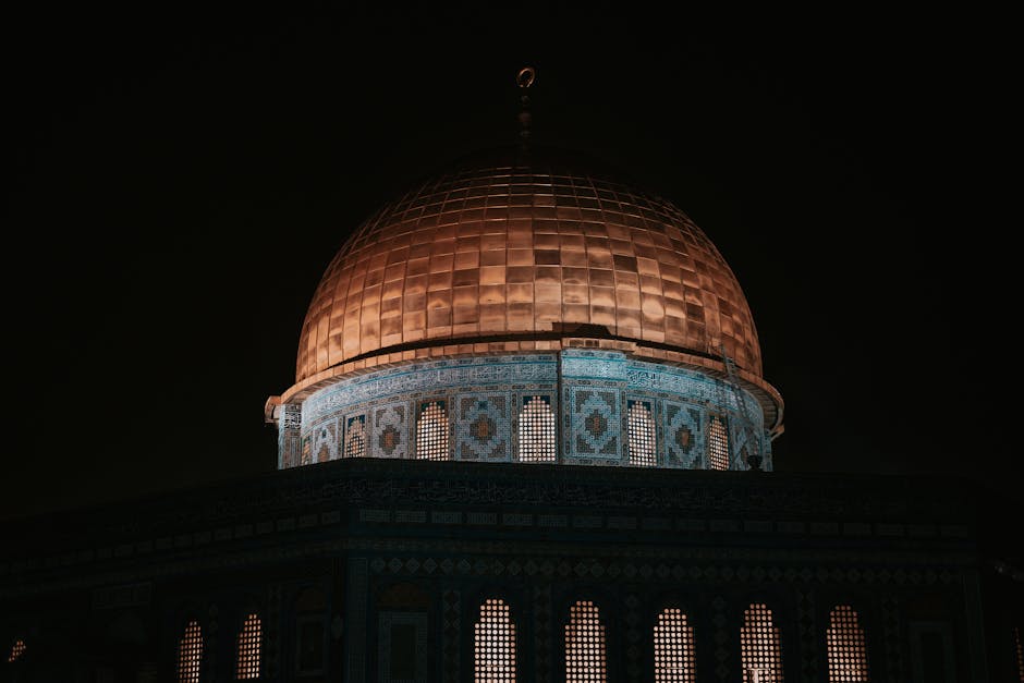 Deskripsi gambar dalam Bahasa Indonesia: Foto sebuah mushaf Al-Quran tua yang terbuka di atas meja kayu di dalam sebuah perpustakaan klasik dengan pencahayaan hangat, dikelilingi oleh tumpukan kitab-kitab kuning klasik karya para ulama terdahulu.