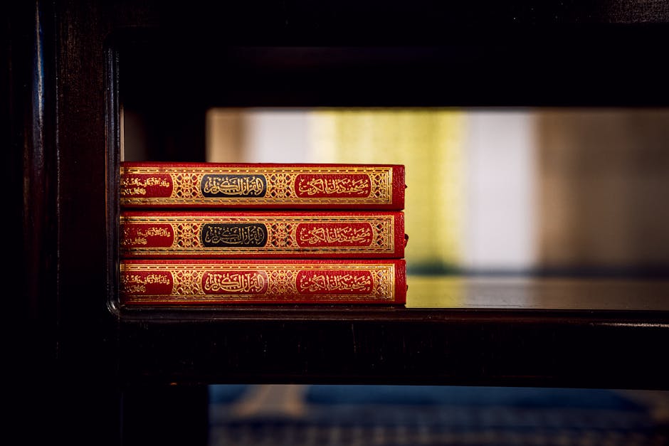 Foto naskah manuskrip hadits kuno yang ditulis dengan khat tsuluts yang indah di atas kertas perkamen tua, dikelilingi oleh kitab-kitab kuning klasik di sebuah perpustakaan Islam tradisional yang tenang.