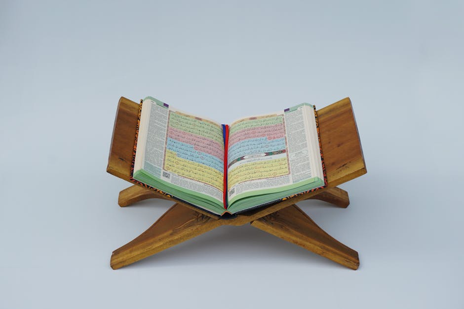 Foto mushaf Al-Quran terbuka di atas meja kayu dengan latar belakang perpustakaan kitab klasik yang penuh dengan naskah-naskah kuno dalam ruangan dengan pencahayaan hangat.