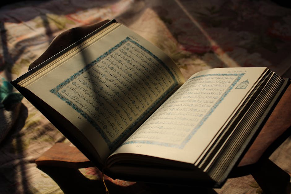Deskripsi gambar dalam Bahasa Indonesia: Foto sebuah naskah kuno Al-Quran dengan tulisan kaligrafi khat tsuluts yang indah di atas meja kayu jati, dikelilingi oleh kitab-kitab klasik di sebuah perpustakaan Islam yang tenang.
